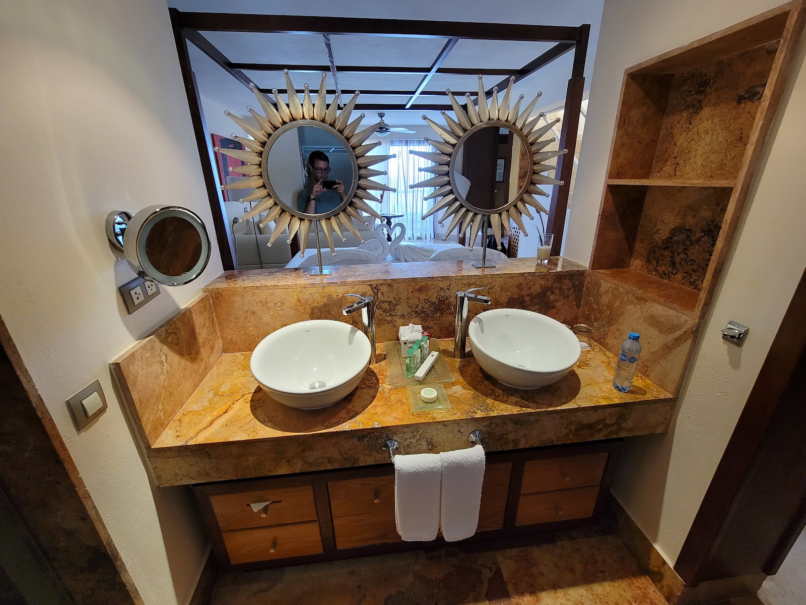Dual-sink bathroom vanity with golden marble countertop, round white vessel sinks, and decorative sunburst mirrors at Finest Playa Mujeres.