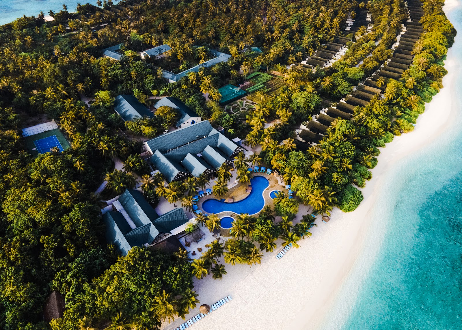 Overwater bungalows with thatched roofs at Furaveri Maldives, featuring private pools and two guests dining in turquoise lagoon water.