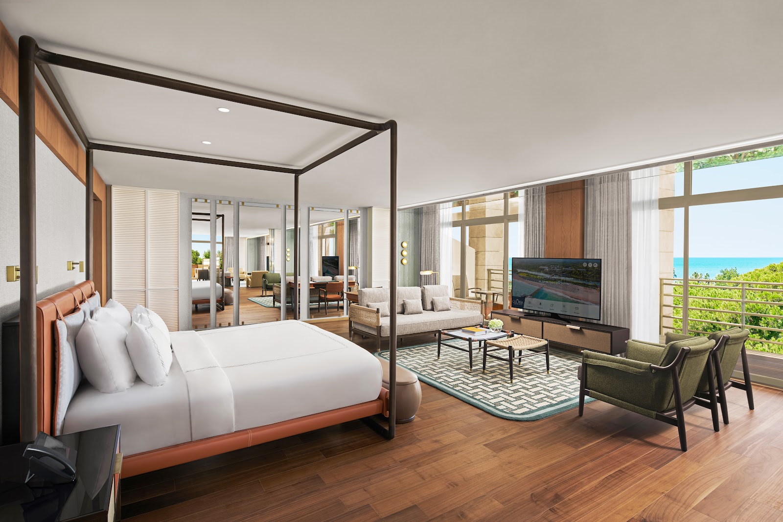 Spacious resort suite with four-poster bed, living area, and ocean views through floor-to-ceiling windows overlooking turquoise water.