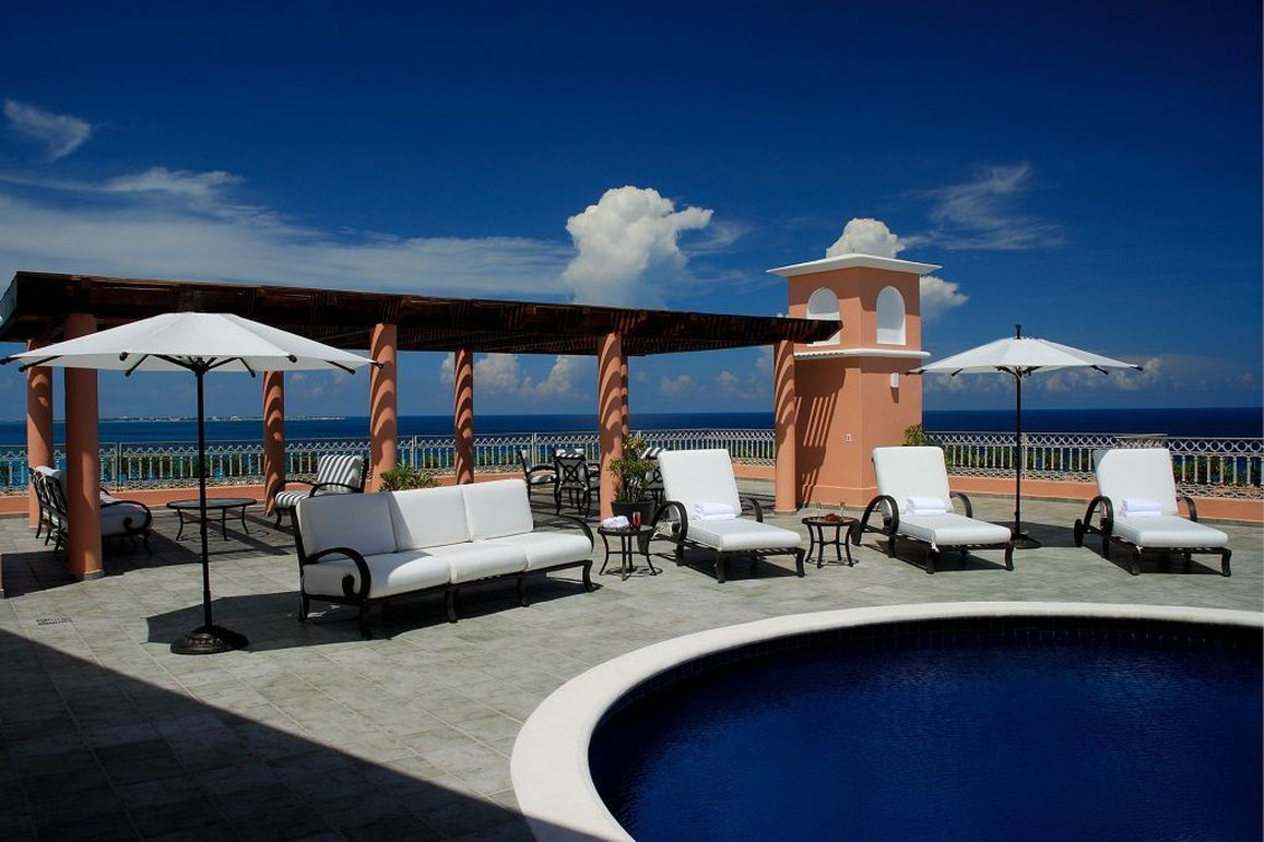 Grand Fiesta Americana Coral Beach's open-air dining pavilion at dusk with set tables, pendant lights, and ocean views beyond.