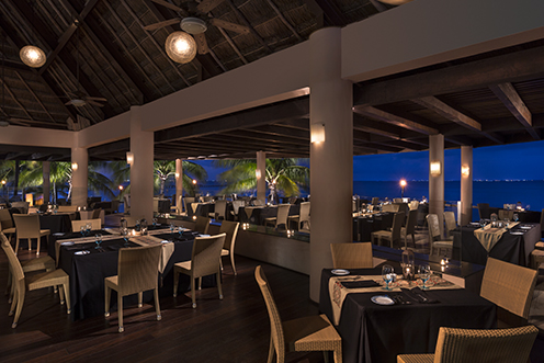 Grand Fiesta Americana Coral Beach resort overlooks turquoise Caribbean waters with curved pools, thatched palapas, and a sandy beach dotted with loungers.