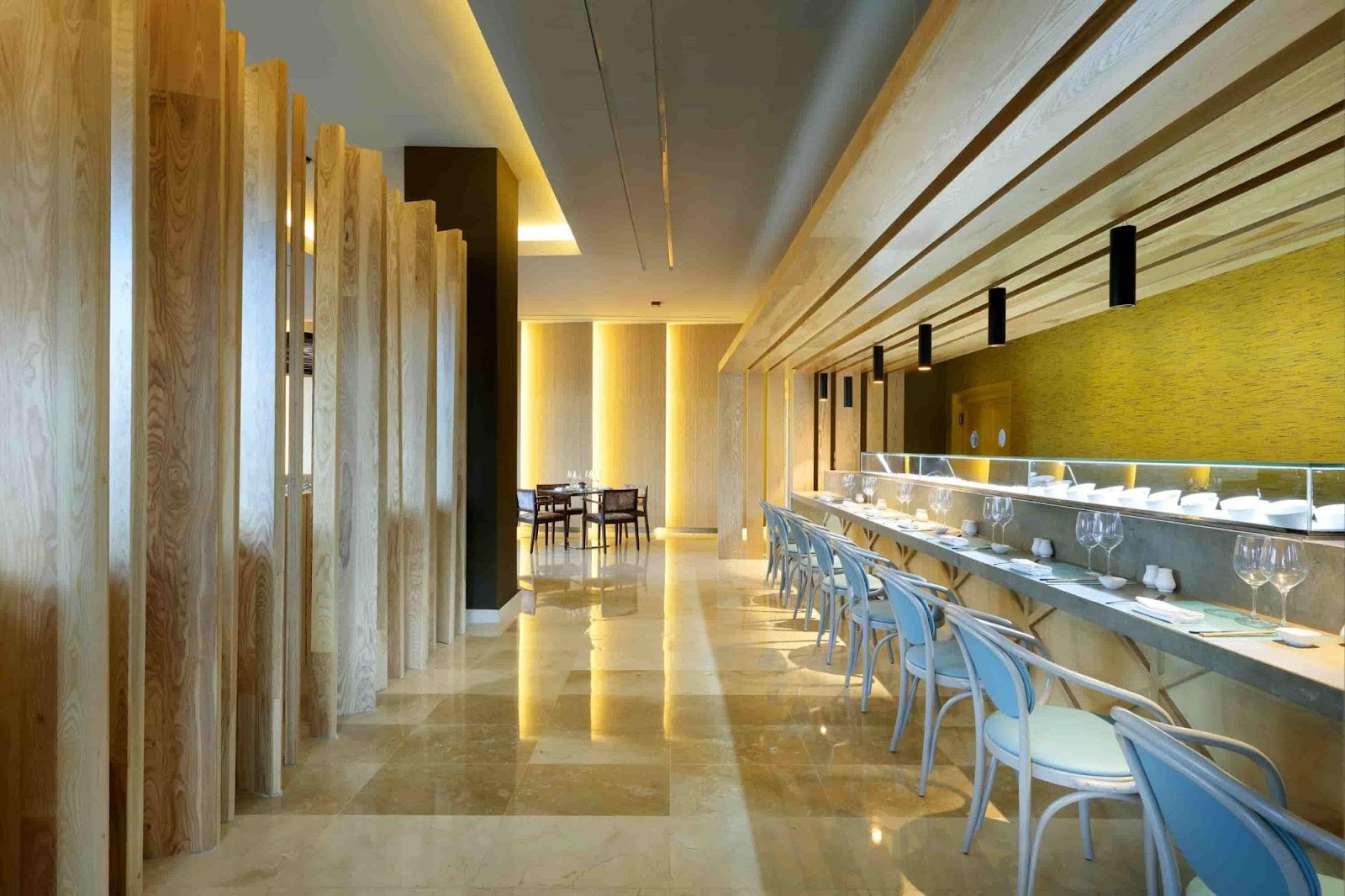 Modern fine dining restaurant with black tables, white chairs, geometric neon lighting, and gold spiral wall art at Grand Palladium Select Bávaro.