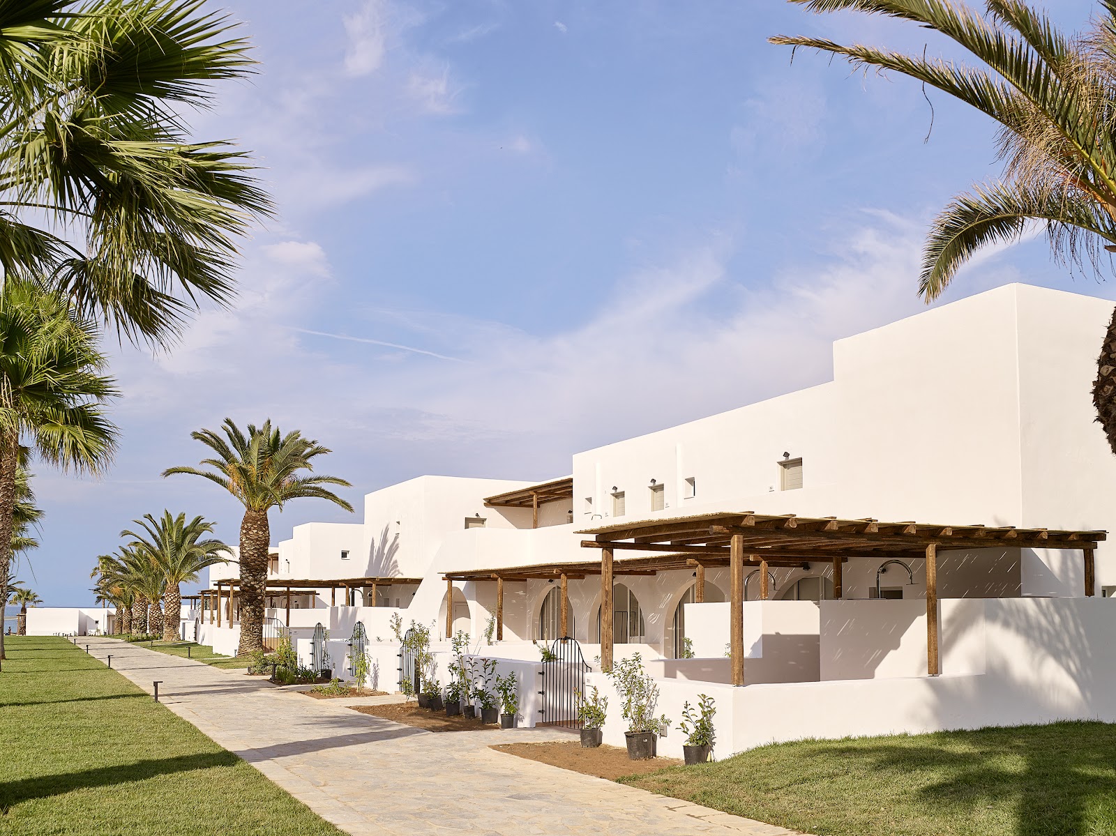 Indoor pool with turquoise water under arched white ceilings, wooden loungers along the sides, and tall wooden structures with pendant lights at Grecotel Casa Marron.