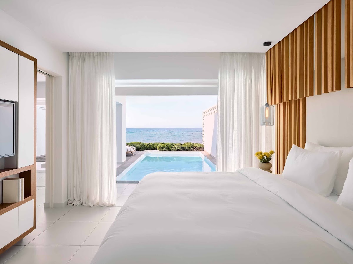 Beachfront suite with two beds, private pool on terrace, and ocean view through floor-to-ceiling curtains at Grecotel LUXME White.