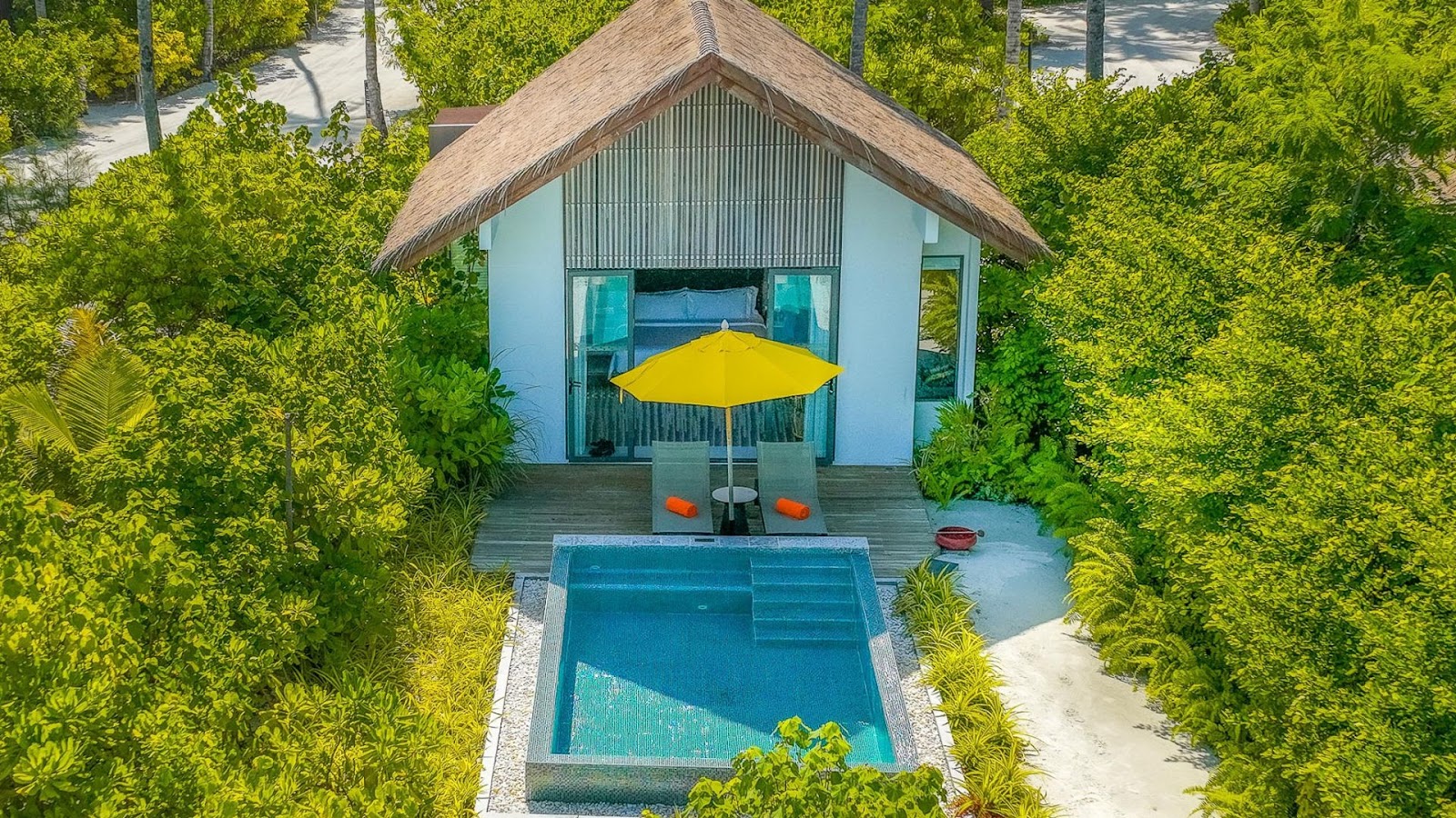 Open-air dining pavilion at Hard Rock Hotel Maldives with blue and red chairs, white umbrellas, and colorful butterfly murals on wooden walls.