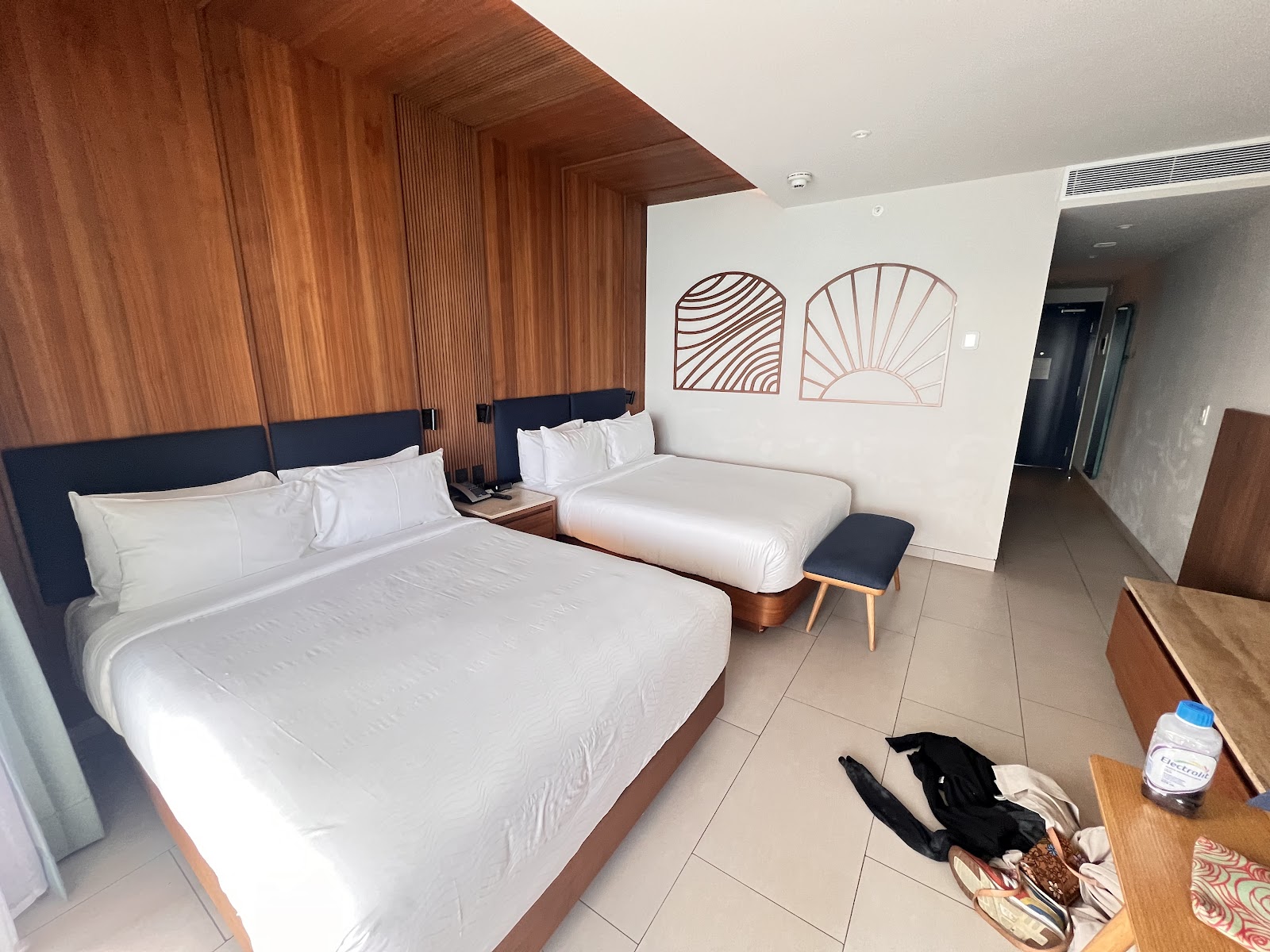 Bedroom with blue bed facing glass doors opening to balcony overlooking turquoise ocean and resort buildings.
