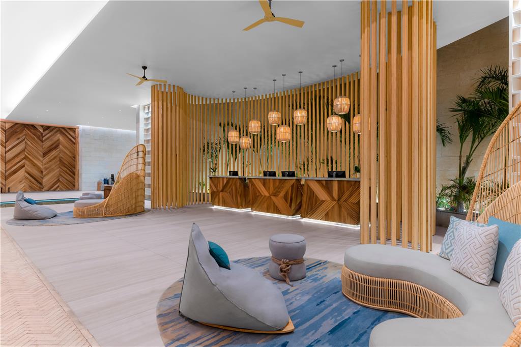 Hilton Tulum Riviera Maya lobby with wooden slat walls, pendant lights, reception desk, and modern seating areas with blue accents.