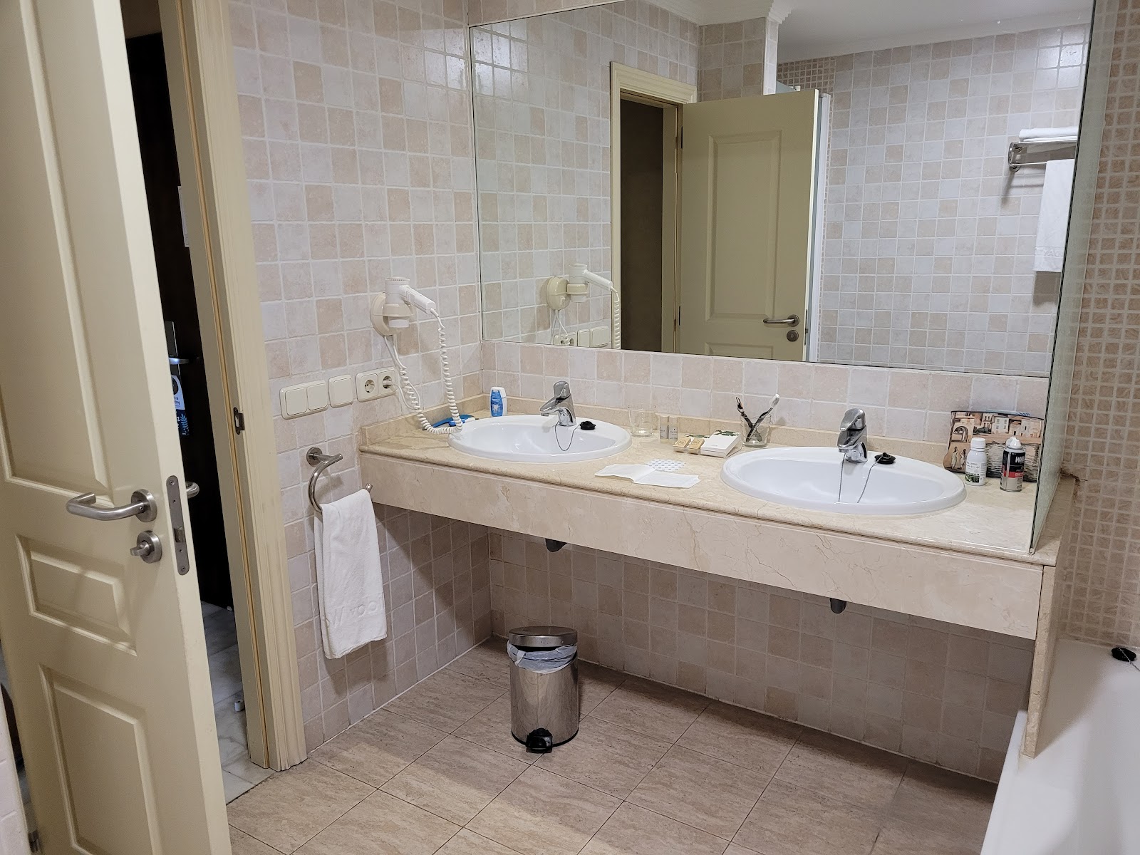 Double vanity with two round sinks, large mirror, and cream tile walls in a resort bathroom.