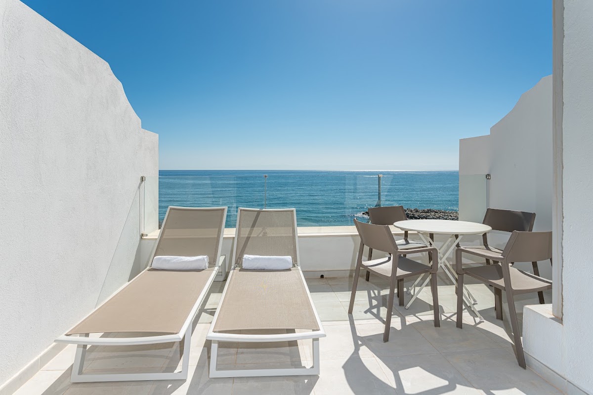 Private terrace at Hotel Benalma Costa del Sol with lounge chairs, dining table, and direct ocean views.