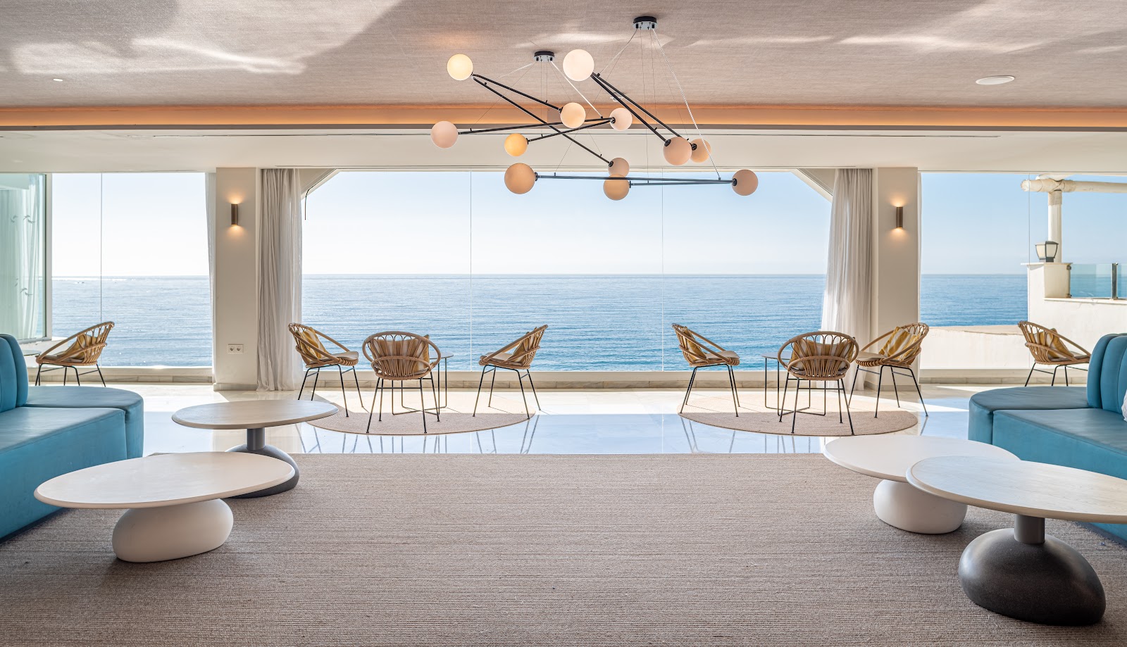 Covered oceanfront dining terrace with woven shade panels, wicker chairs, and tables set for service overlooking the Mediterranean Sea.