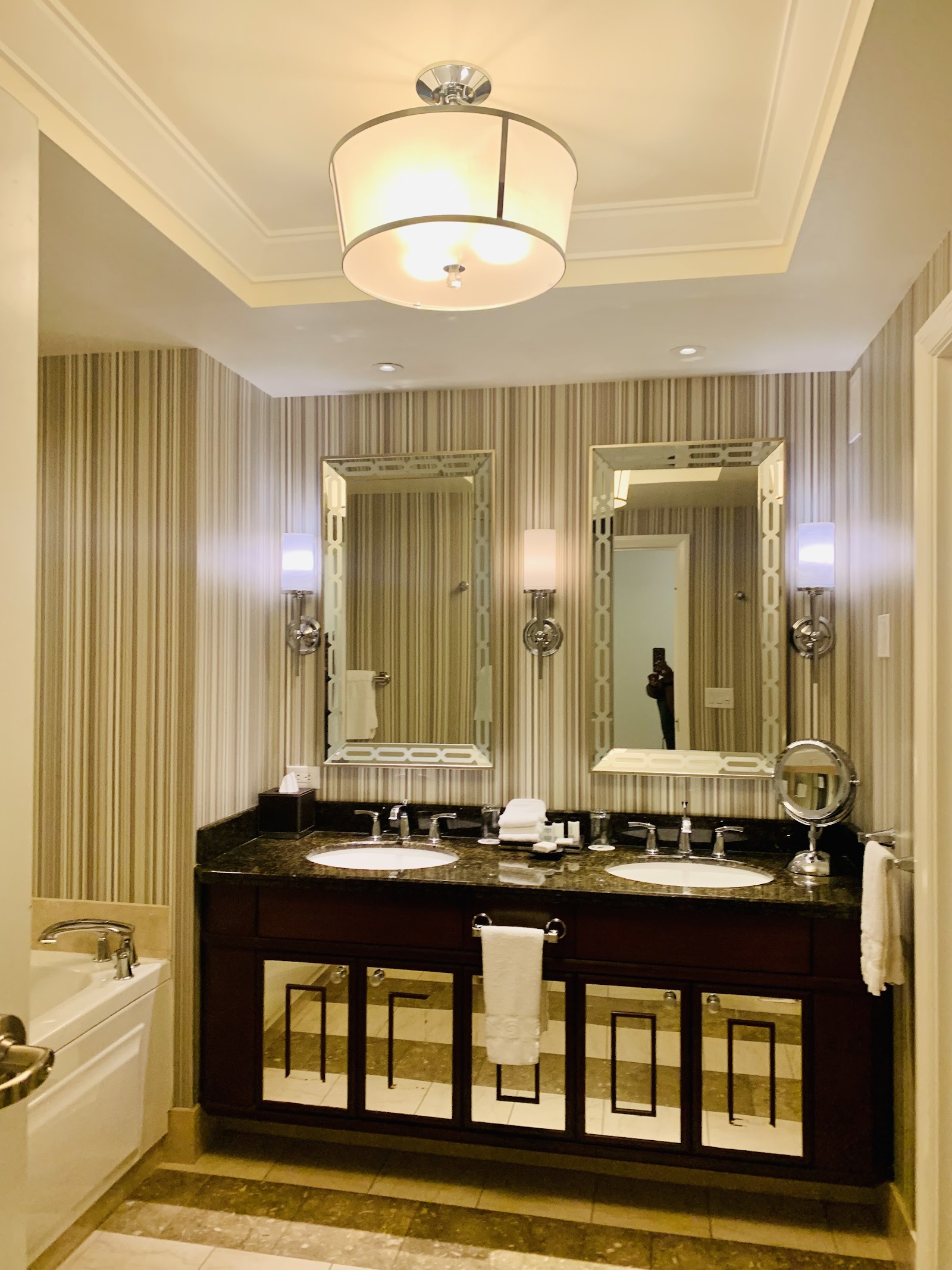 Bathroom with dual sinks, dark wood vanity, framed mirrors, and a soaking tub with glass shower enclosure.