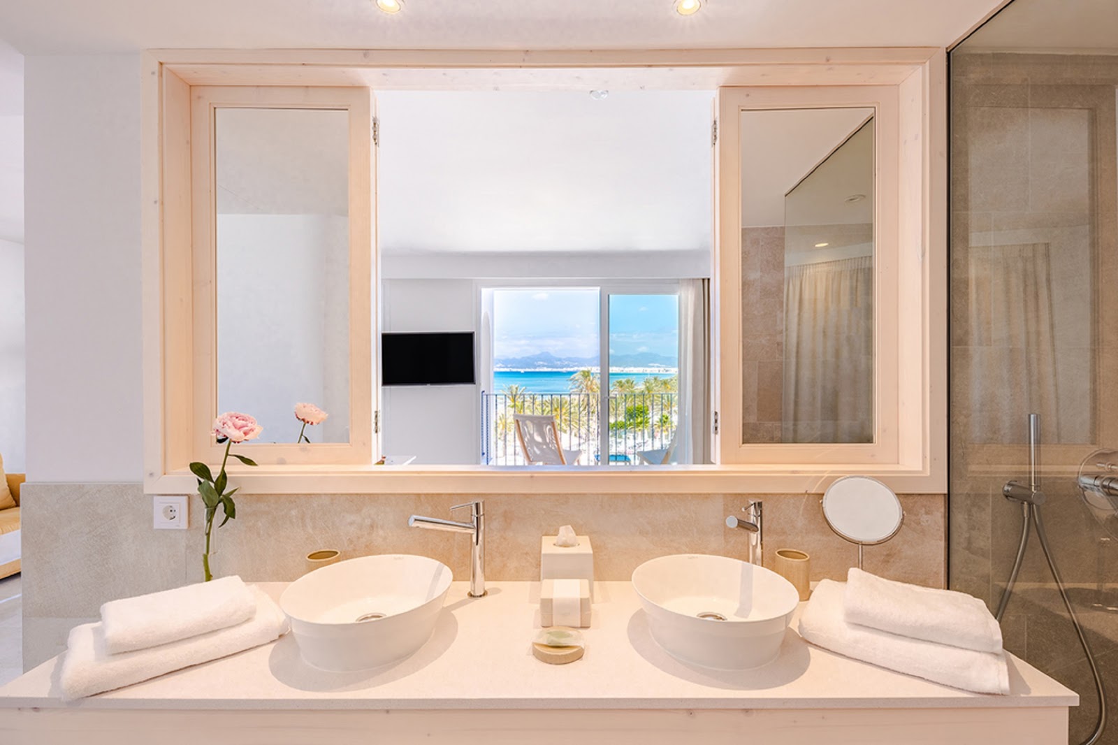 Double vessel sinks in a modern bathroom with ocean and mountain views through the balcony doors at Hotel MySeaHouse Flamingo.