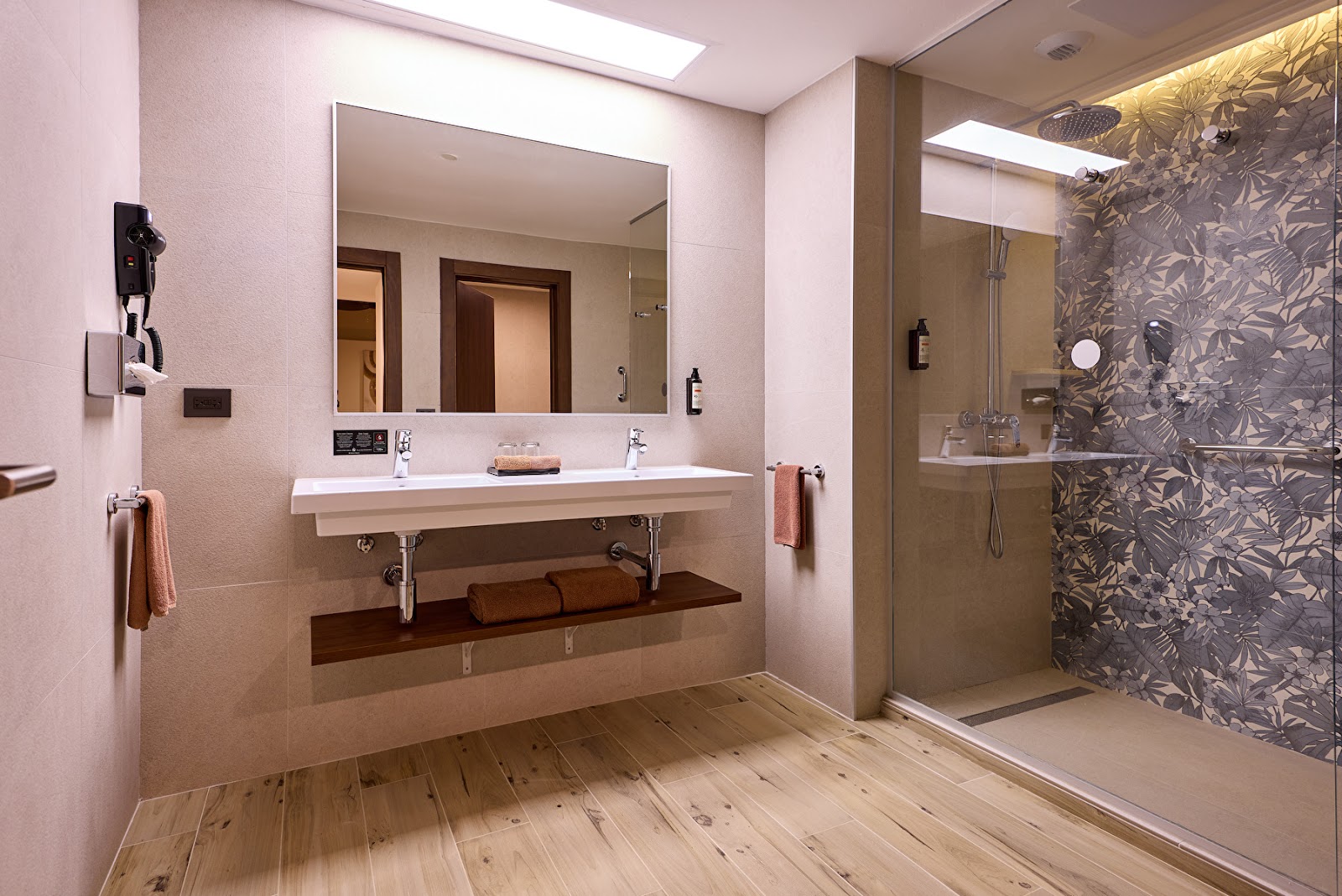 Bathroom vanity with four white round sinks set in speckled granite countertop, toiletries and towels visible.