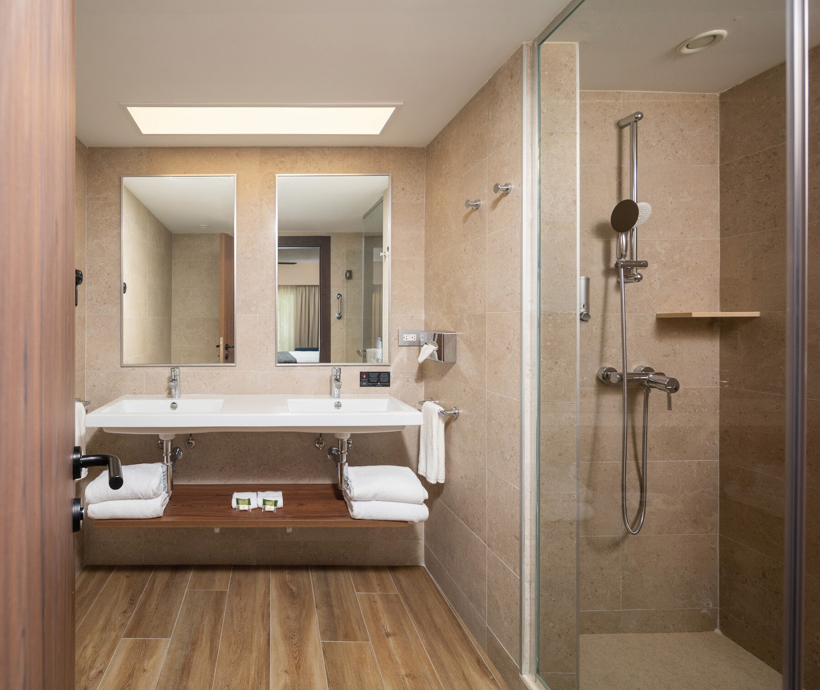 Spacious bathroom with dual sinks, large mirrors, walk-in shower, and wood-look flooring at Hotel Riu Montego Bay.