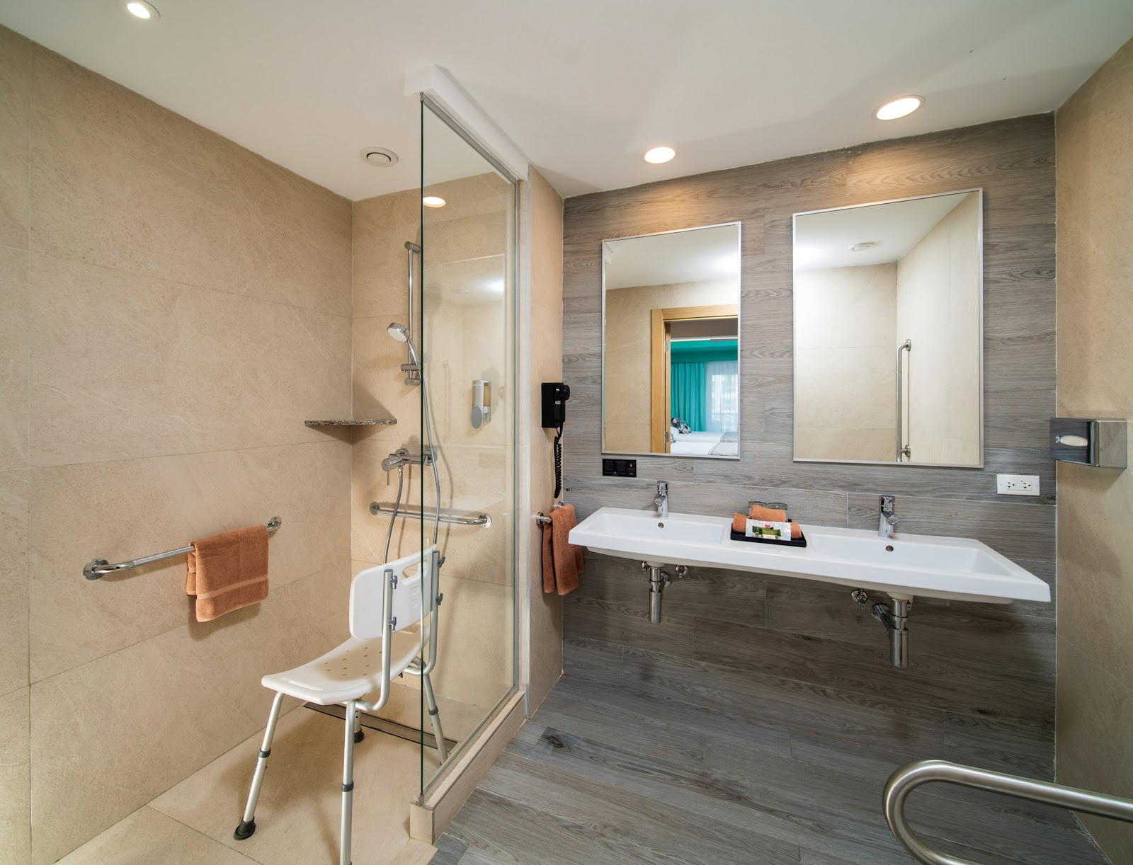Accessible bathroom with walk-in shower, dual vanity sinks, large mirrors, and safety grab bars throughout.