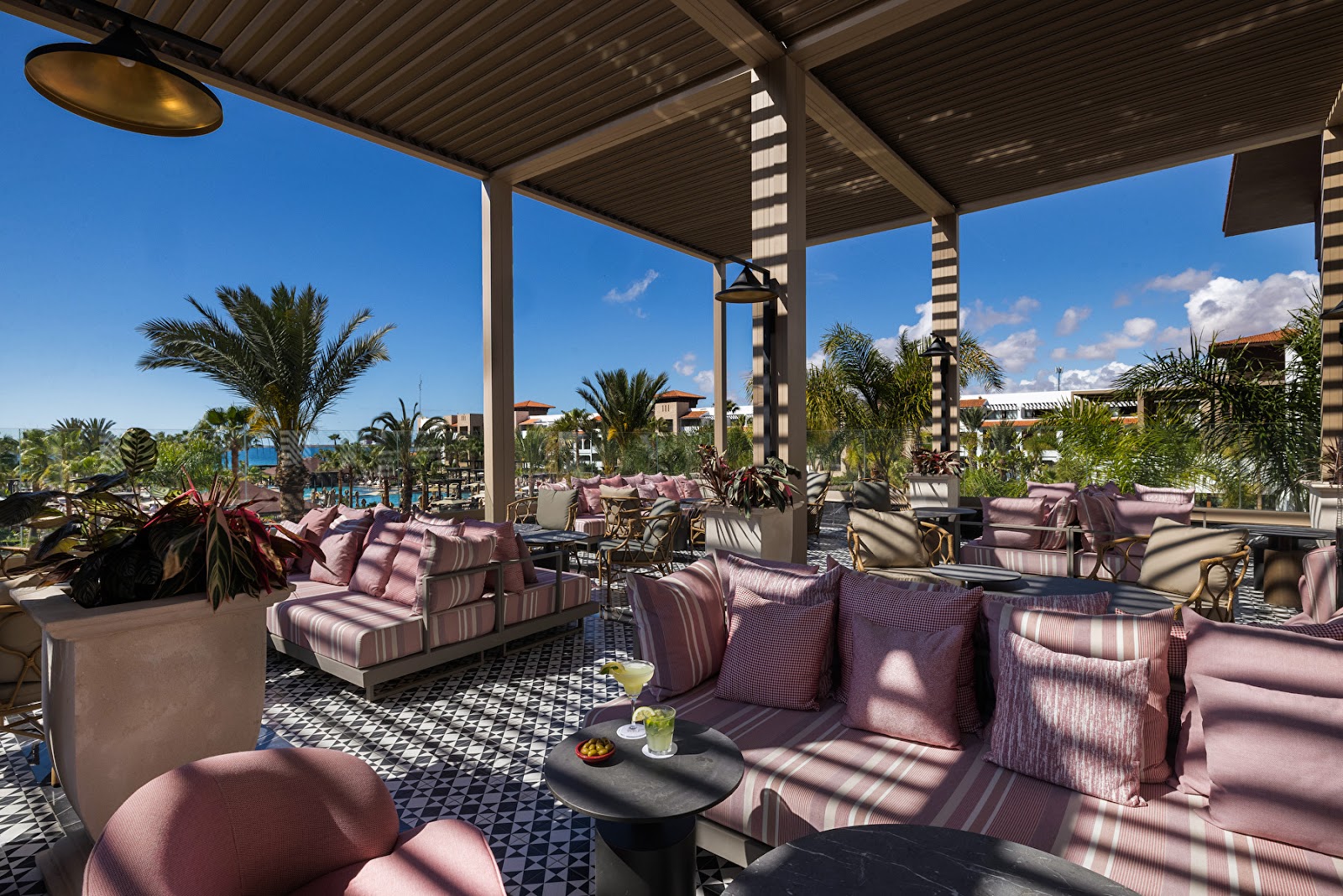Indoor swimming pool with striped blue tiles, lounge chairs lining the deck, and coffered ceiling with skylights at Hotel Riu Palace Tikida Agadir.