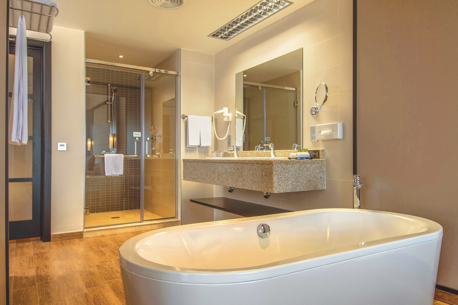 Modern bathroom with freestanding white tub, large mirror, walk-in shower with glass enclosure, and granite countertops at Hotel Riu Sri Lanka.