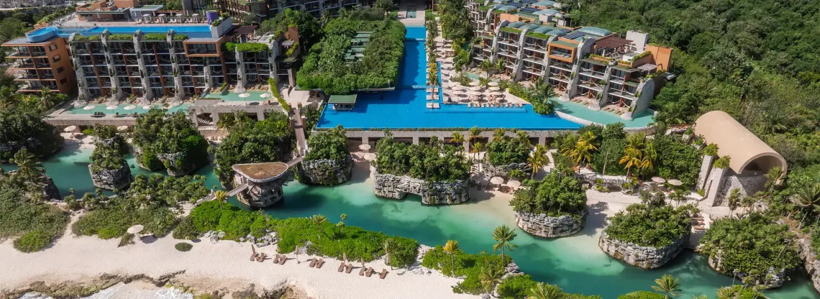 Private balcony with lounge chair and rope hammock overlooks turquoise cenote waters and lush jungle at Hotel Xcaret Arte.