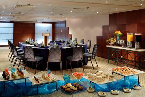 Hurghada Marriott Beach Resort banquet room with round tables, catering stations, and buffet platters of food and drinks displayed on blue-draped tables.
