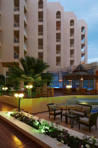 Hurghada Marriott Beach Resort at dusk with illuminated poolside seating, palm trees, and multi-story pink building facade.