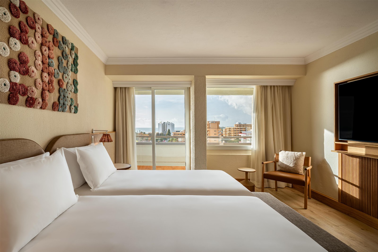 Double bed guestroom with balcony overlooking a river and cityscape at Hyatt Regency Vilamoura Algarve.