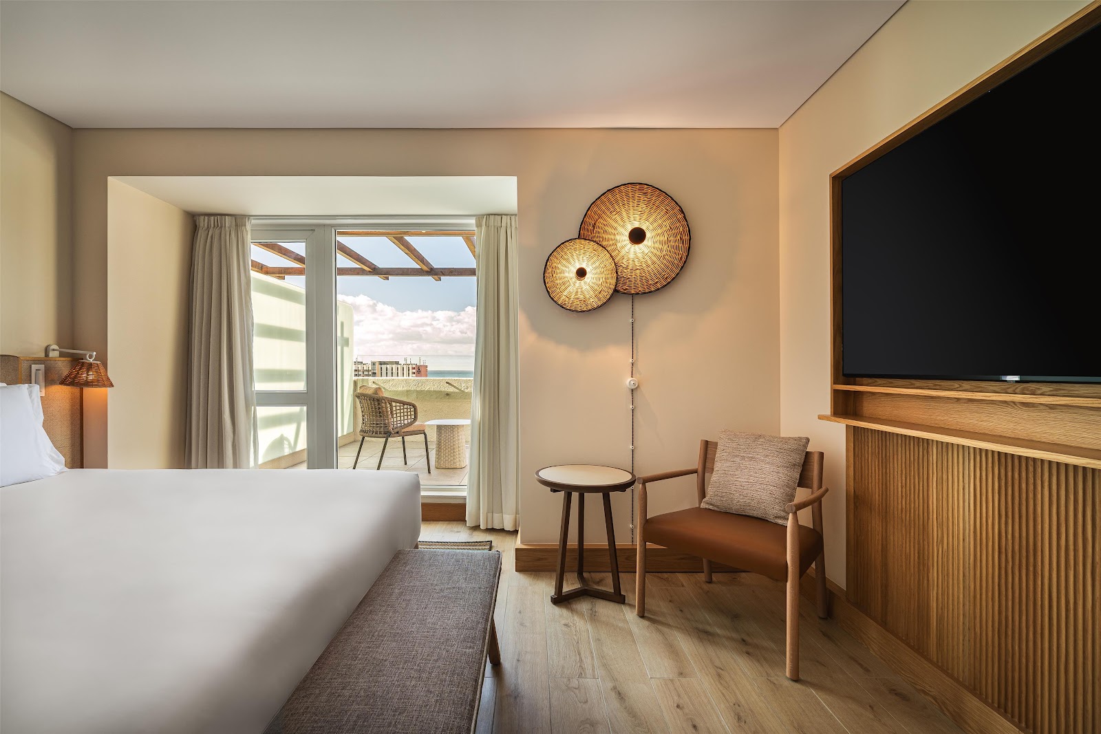 Spacious lobby lounge at Hyatt Regency Vilamoura Algarve with cream sofas, wooden tables, pendant lights, and floor-to-ceiling windows overlooking tropical grounds.
