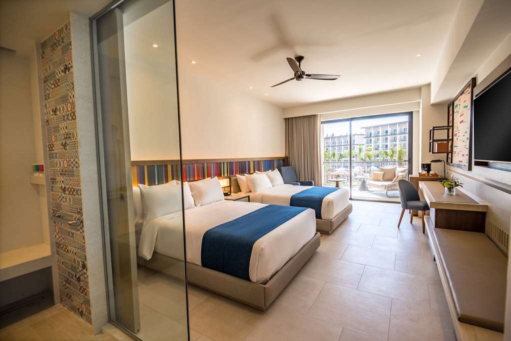 Modern hotel room with two queen beds, colorful striped headboard, and ocean-view balcony at Hyatt Zilara Cap Cana.