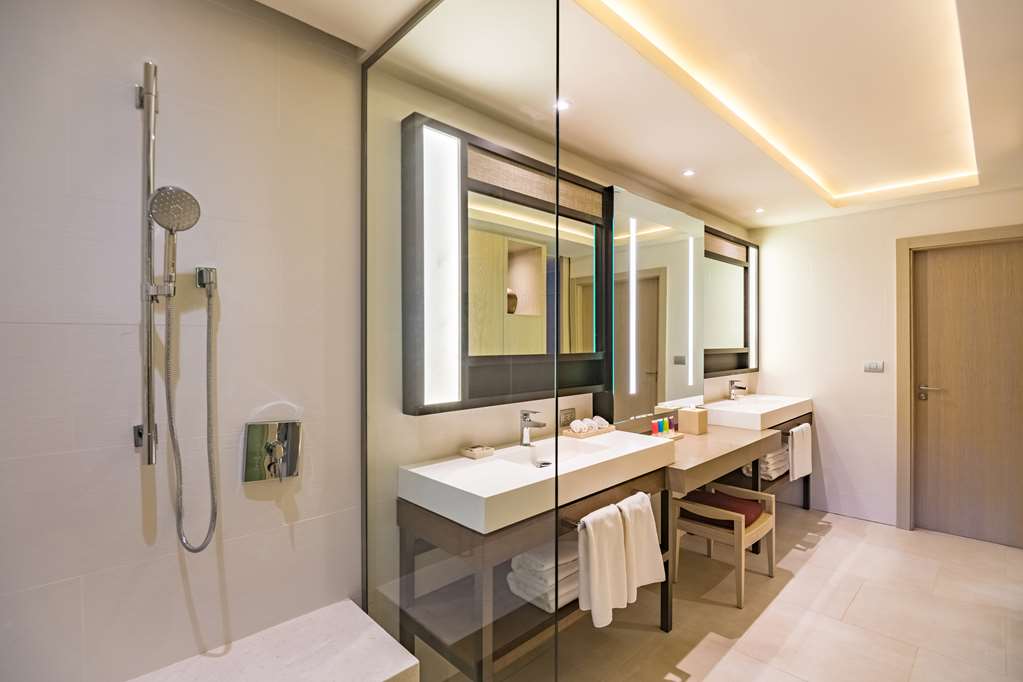 Modern bathroom with dual vanities, illuminated mirrors, glass shower enclosure, and neutral tile throughout at Hyatt Zilara Cap Cana.
