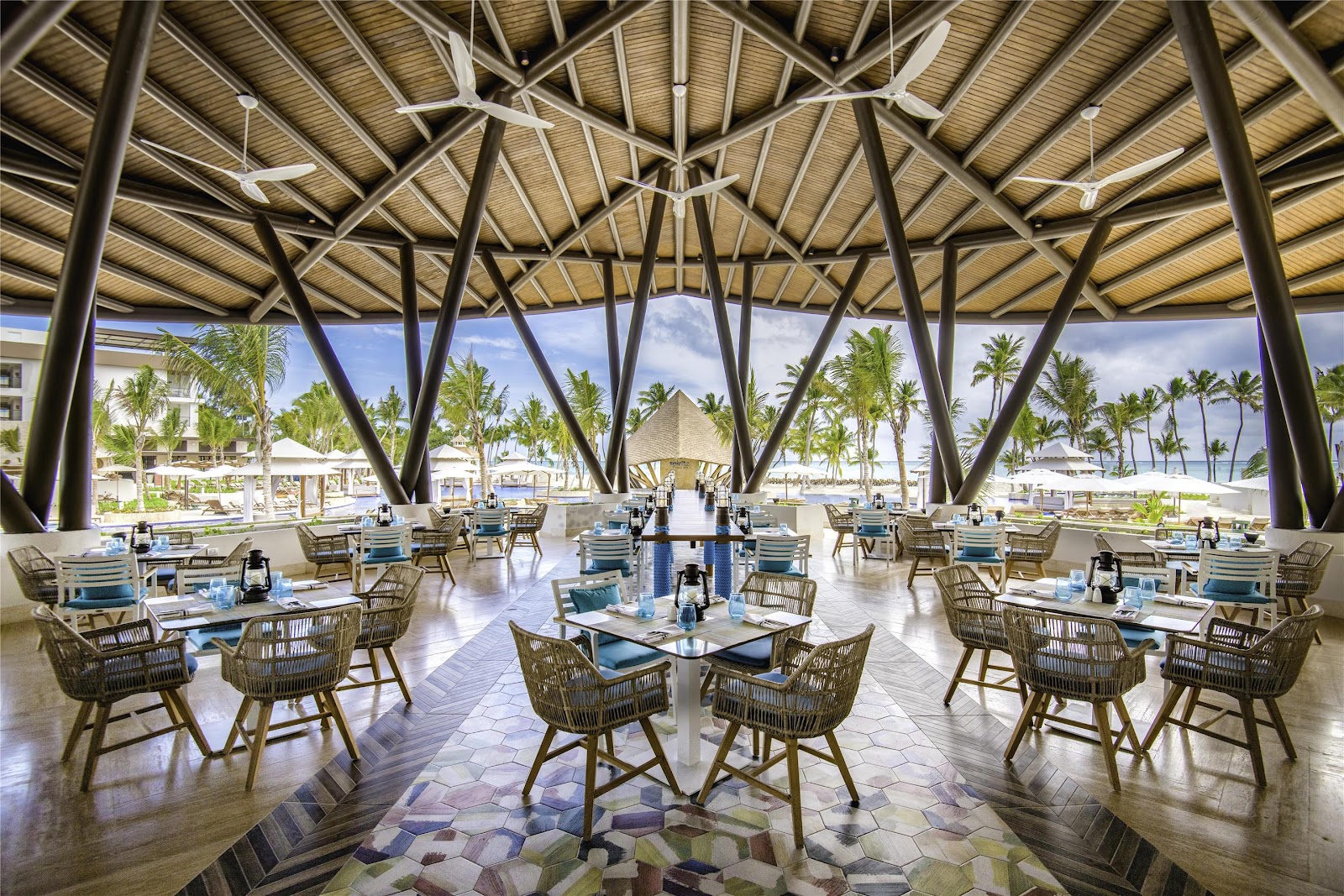 Beige sofa and dining furniture on a balcony overlooking palm trees and ocean under clear blue sky at Hyatt Ziva Cap Cana.