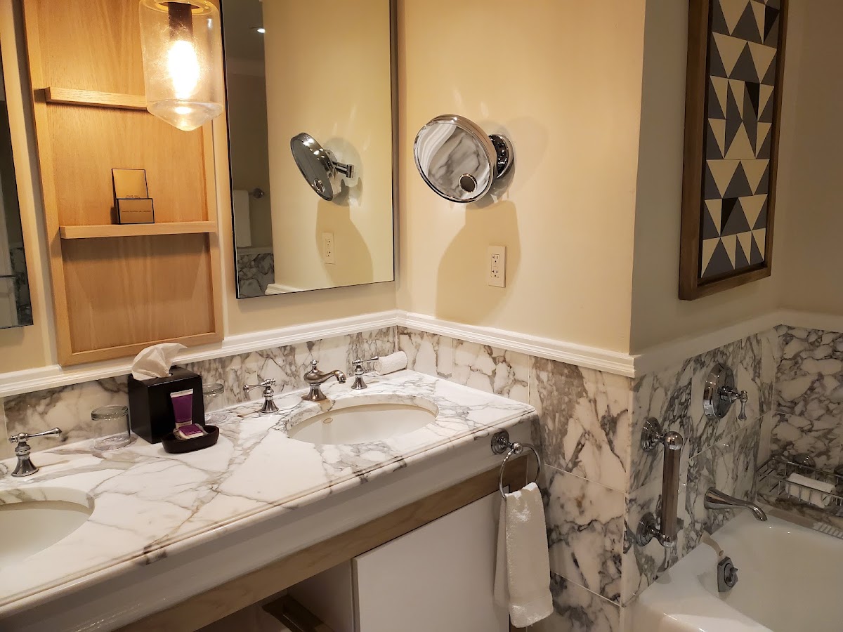 Resort bathroom with marble countertop, dual round mirrors, single sink, and decorative black and white geometric art on walls.