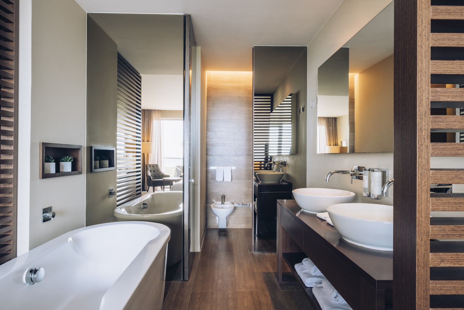 Spa bathroom with two white vessel sinks, dual soaking tubs, wood flooring, and heated towel racks at Iberostar Selection Lagos Algarve.