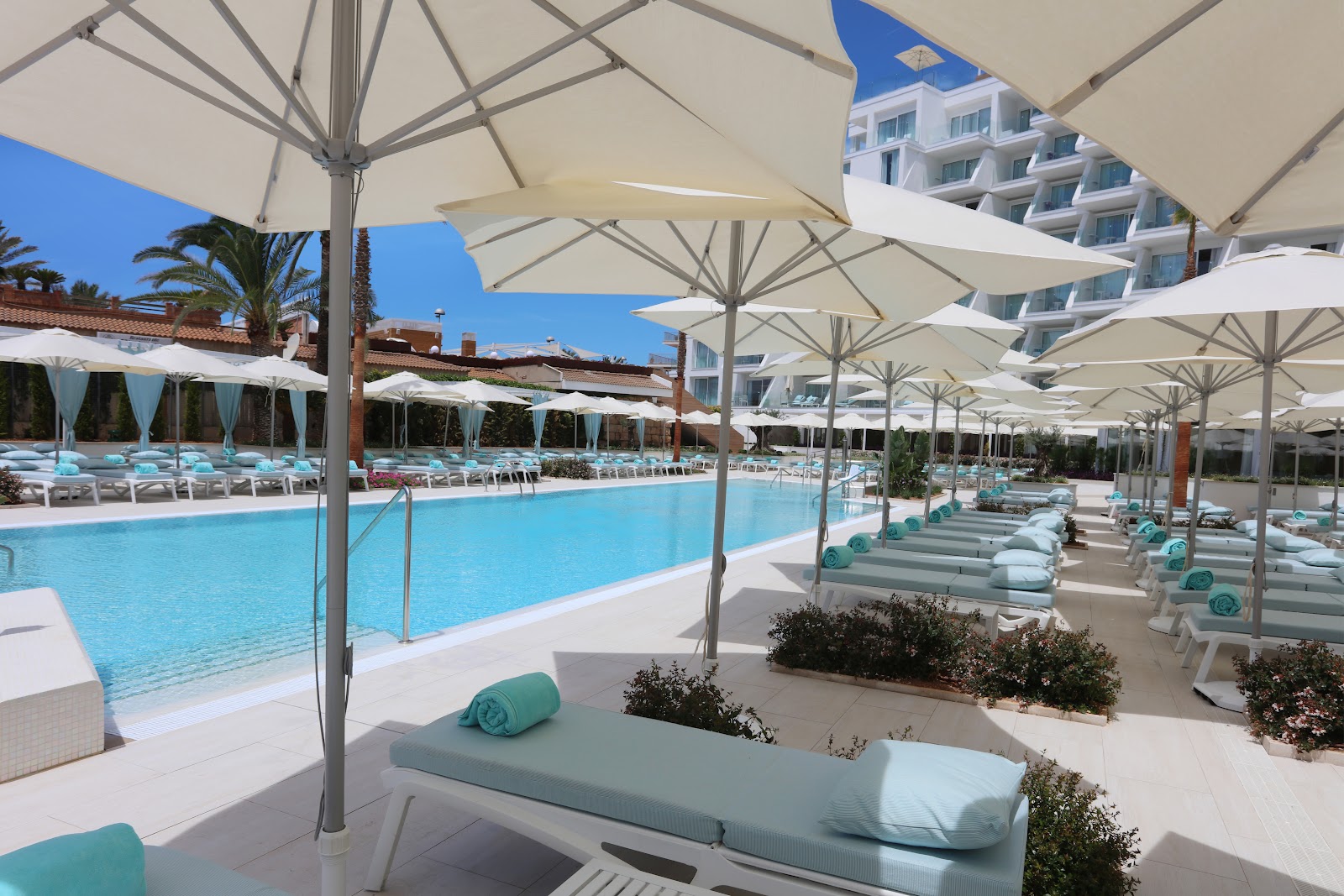 Shaded wooden deck with hanging egg chairs, loungers, and ocean view under beige sail canopies at Iberostar Selection Playa de Palma.