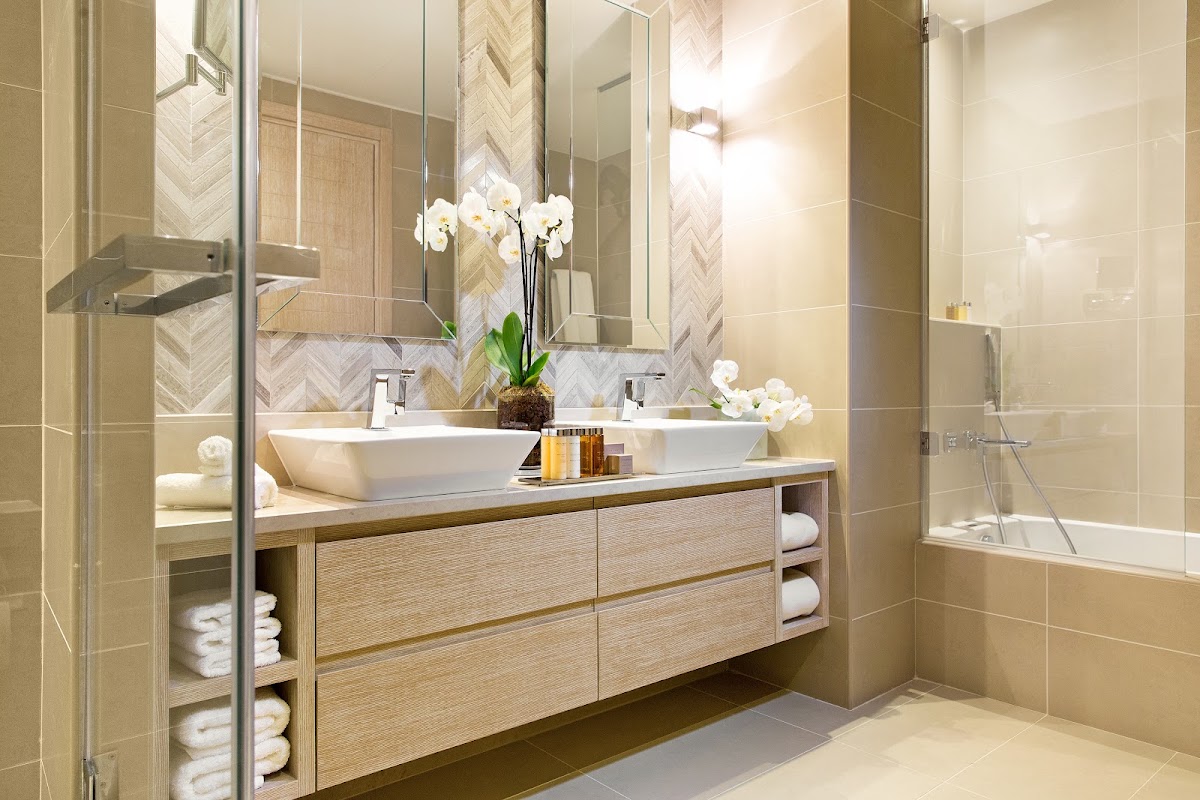 Spacious bathroom with dual vessel sinks, herringbone tile backsplash, walk-in shower, and wooden vanity with white orchids at Ikos Oceania.