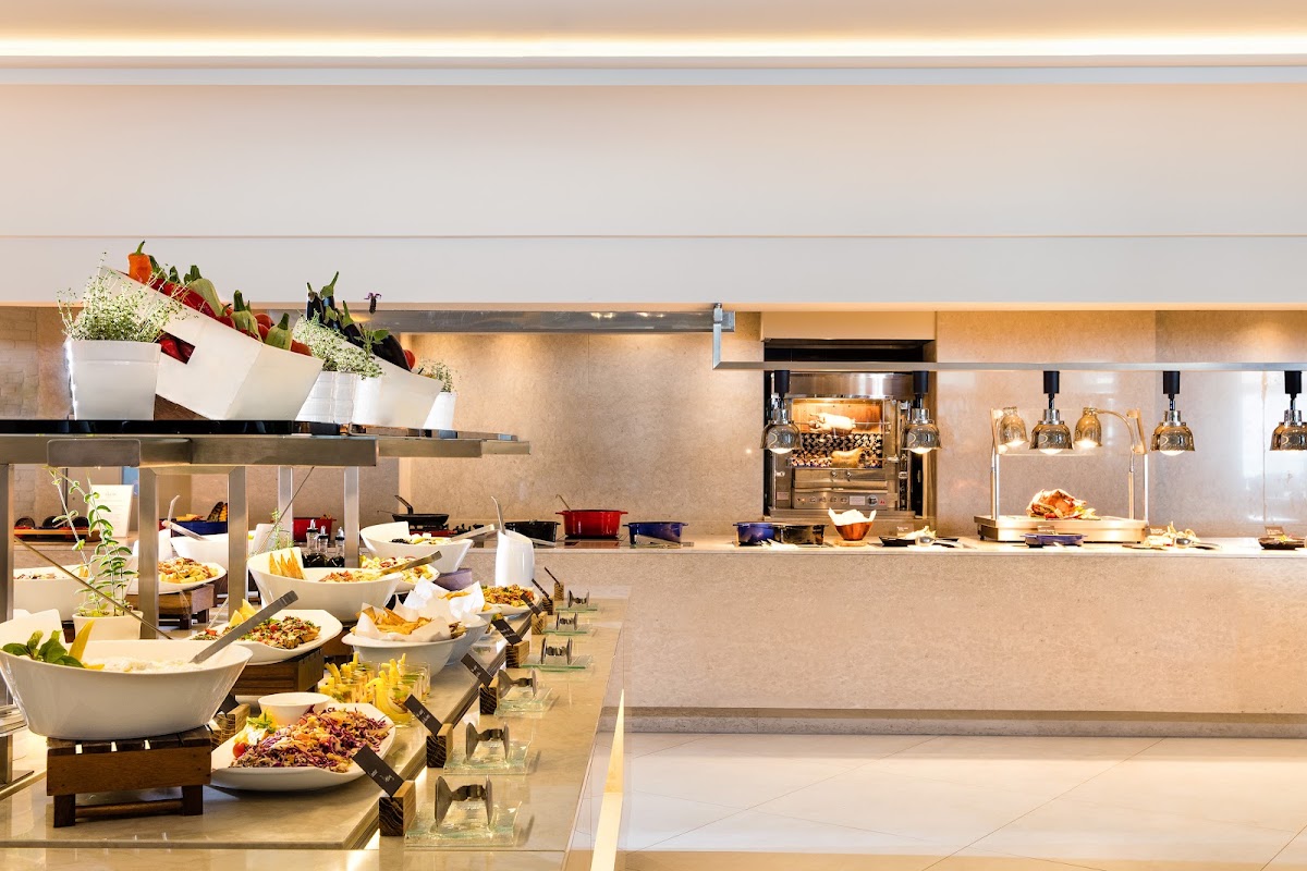 Modern buffet dining area with plated dishes, fresh flowers, and open kitchen at Ikos Oceania.