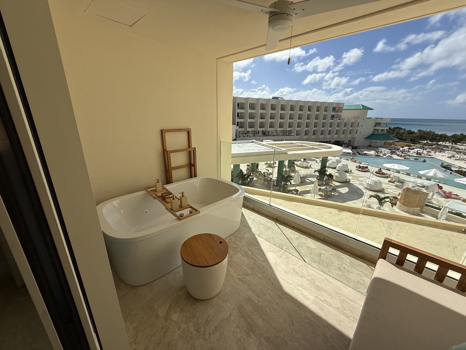 Bathroom with soaking tub and ocean view overlooking JOIA Aruba's pool, beach, and turquoise water under blue sky.