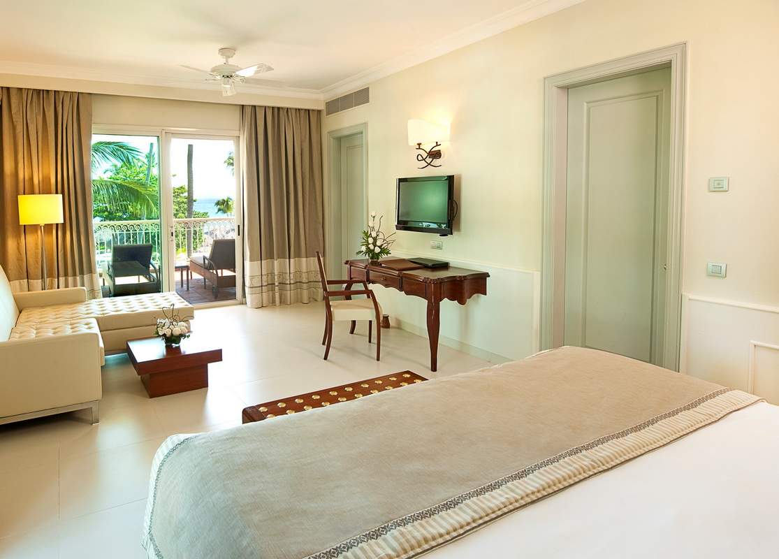 Spa treatment room with two massage tables, sink vanity, private shower stalls, and window with potted orchid at JOIA Bávaro by Iberostar.