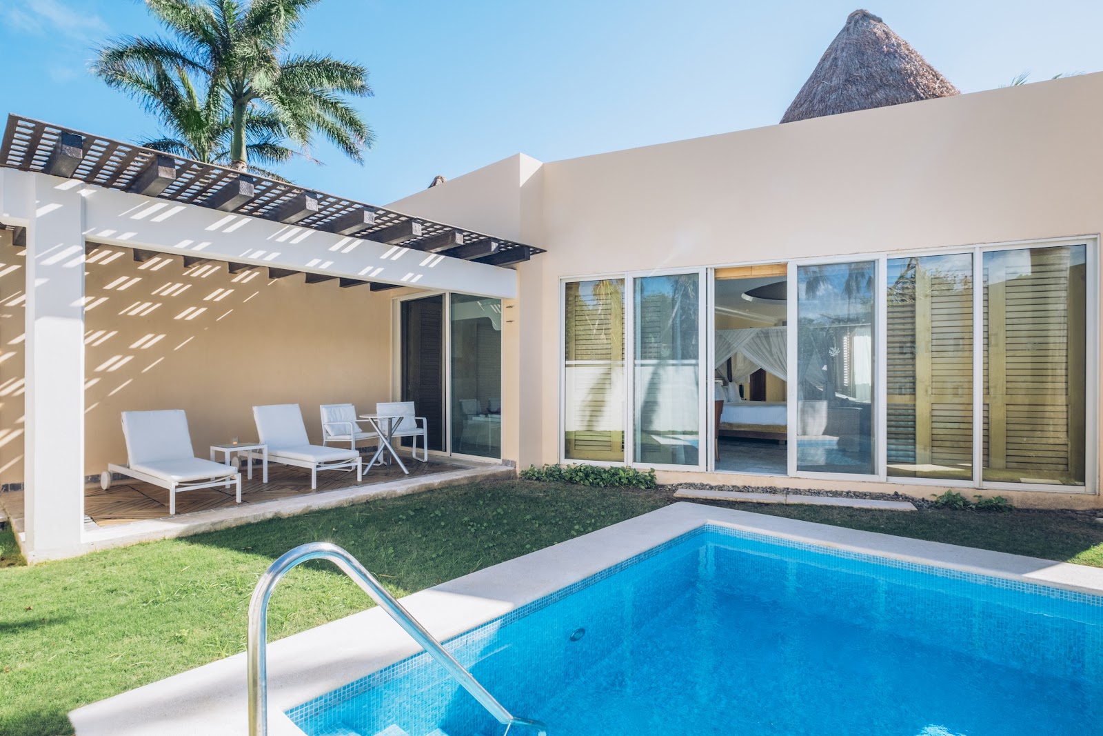Modern beachfront suite with private pool, lounge chairs under pergola, and thatched-roof buildings at JOIA Paraíso by Iberostar.