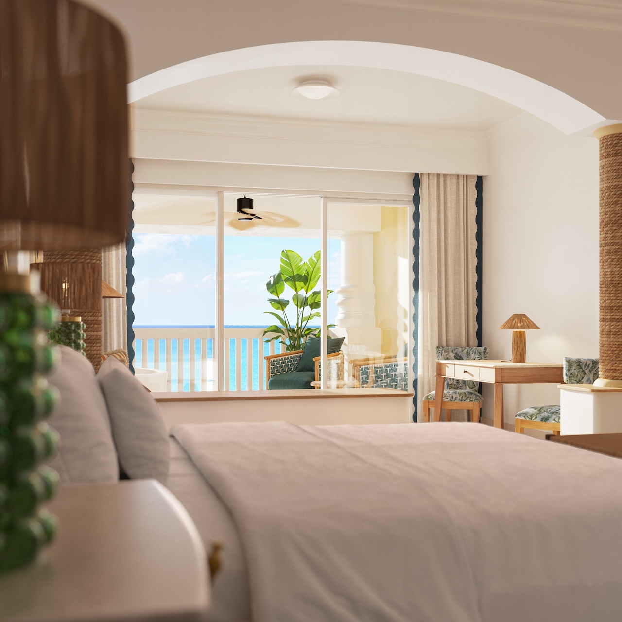 Resort guestroom with flat-screen TV on wooden dresser, bed with patterned runner, and ocean view from balcony with hanging chair.