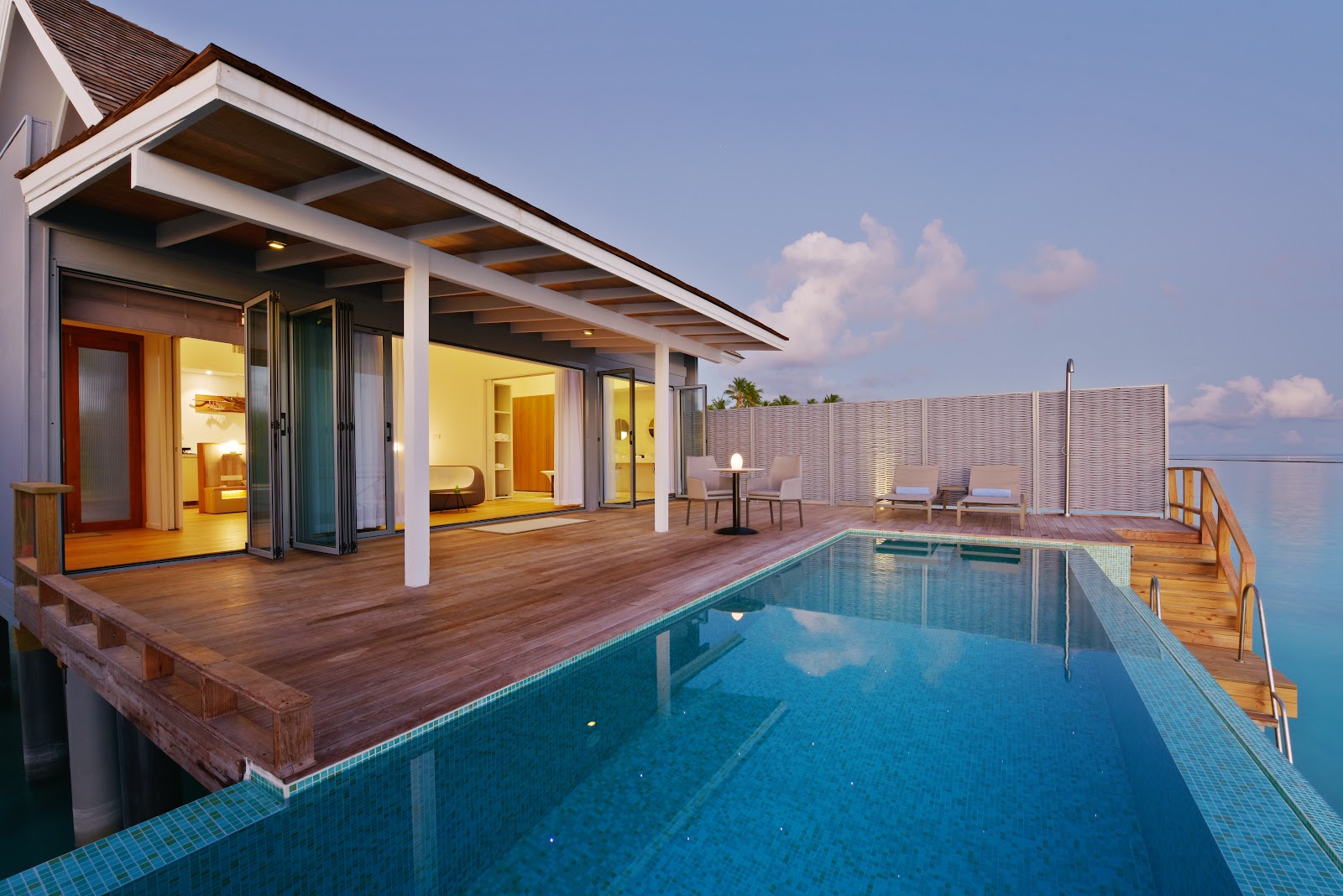 Overwater bungalow at Kuramathi Island Resort with private pool, wooden deck, and ocean views under clear sky.