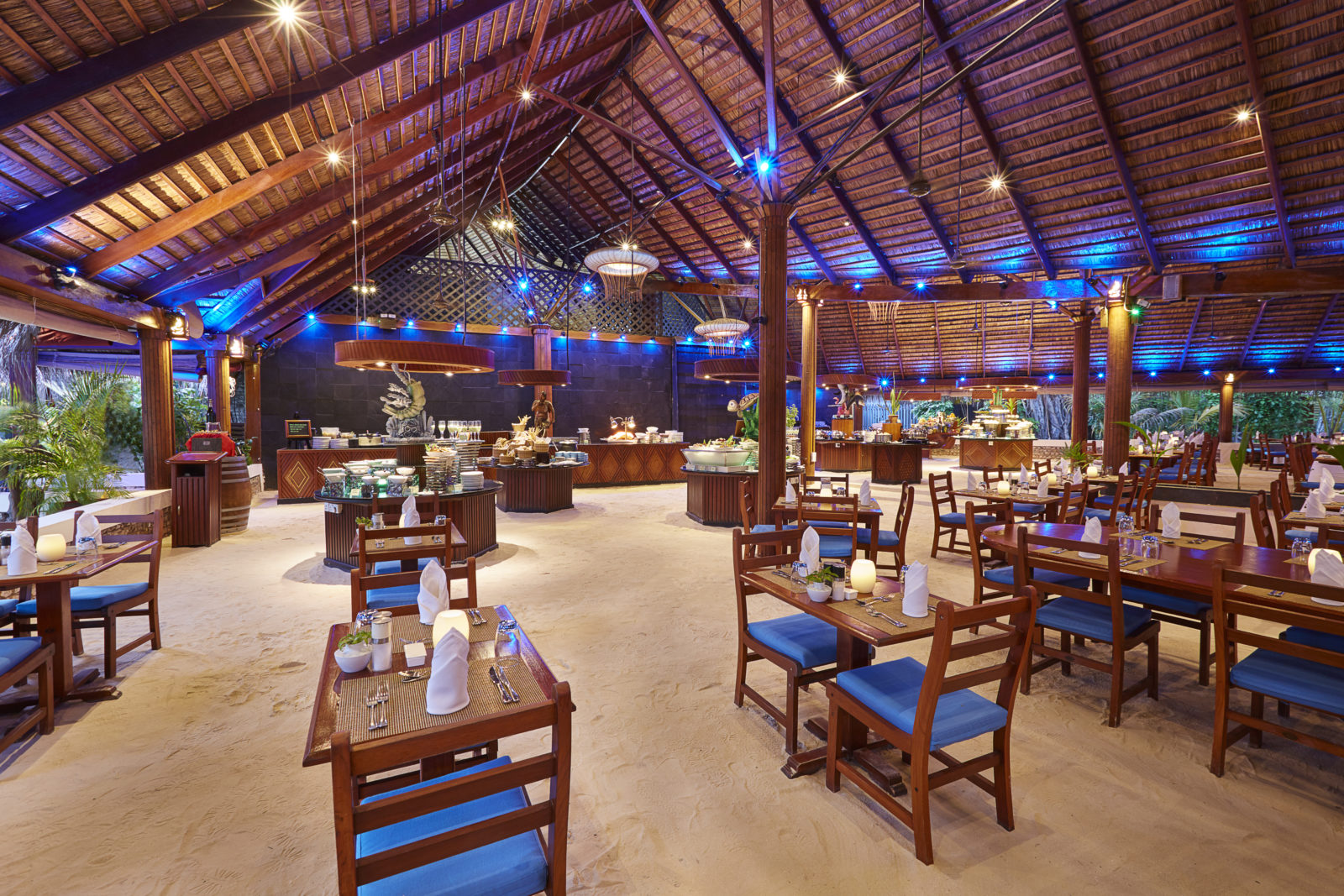 Beachfront dinner setup at Kuredu Island Resort with white draped fabric, candlelit table, and ocean view at sunset.