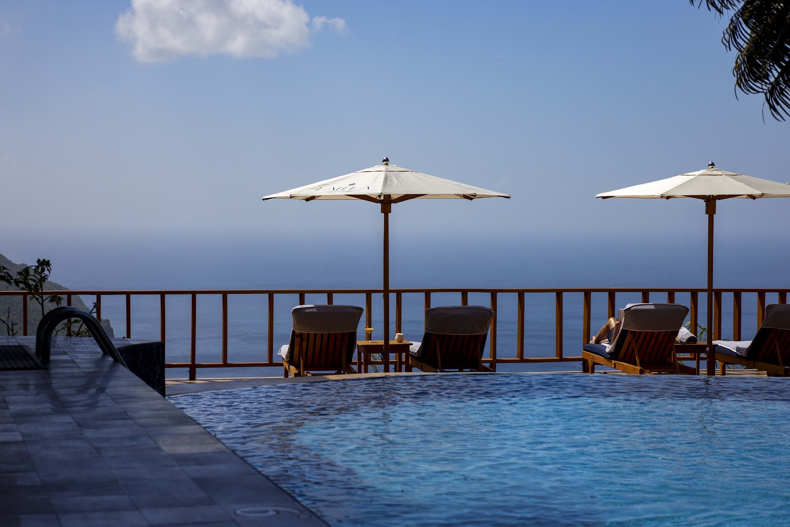 Infinity pool with loungers and cream umbrellas overlooking the Caribbean Sea at Ladera Resort.