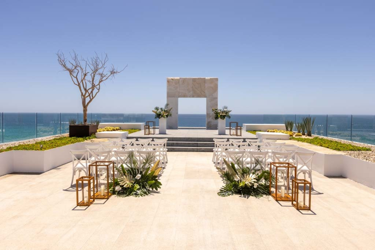Oceanfront wedding ceremony setup at Le Blanc Spa Resort Los Cabos with white chairs, stone archway, and sea views.