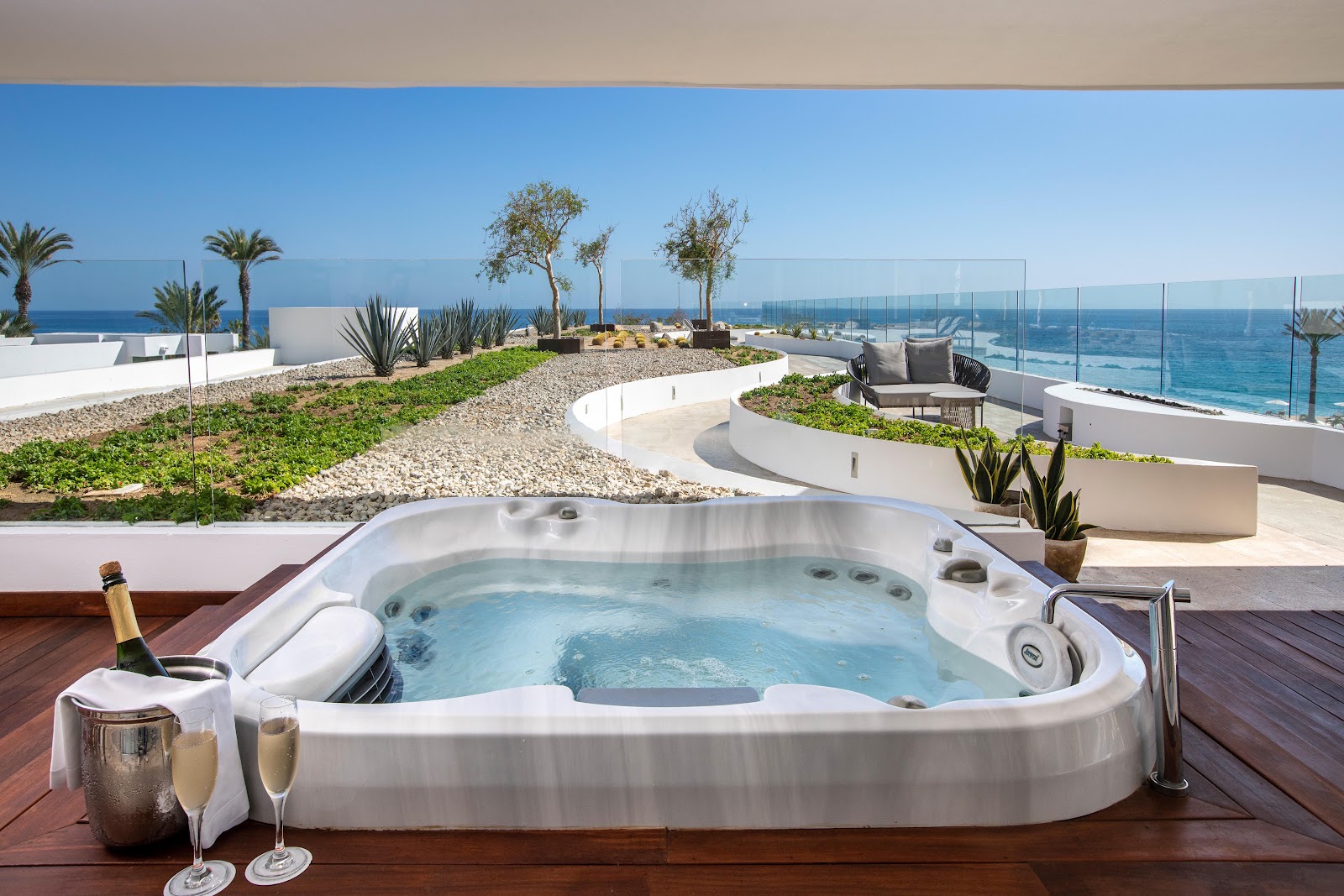 Rooftop hot tub with champagne and ocean view at Le Blanc Spa Resort Los Cabos, overlooking the sea and palm trees.
