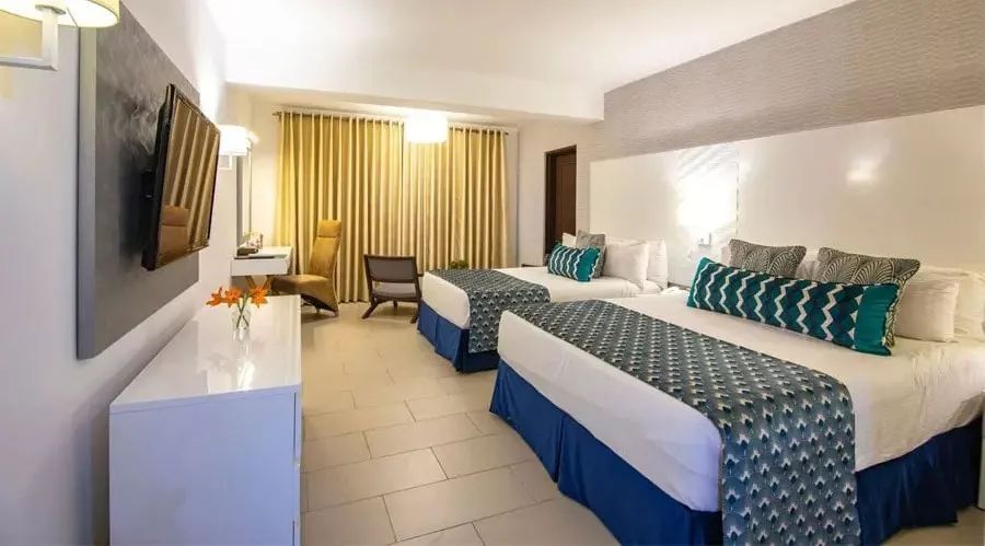 Spacious resort room with two double beds, flat-screen TV, yellow curtains, and seating area at Leopard Beach Resort & Spa.