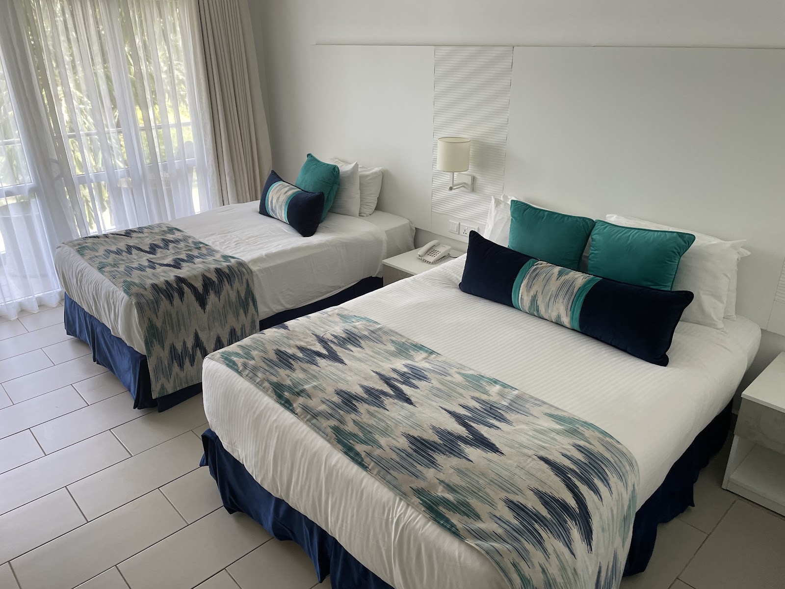 Leopard Beach Resort & Spa beach area with palm trees, thatched umbrellas, and turquoise ocean waters visible beyond the white sand shore.
