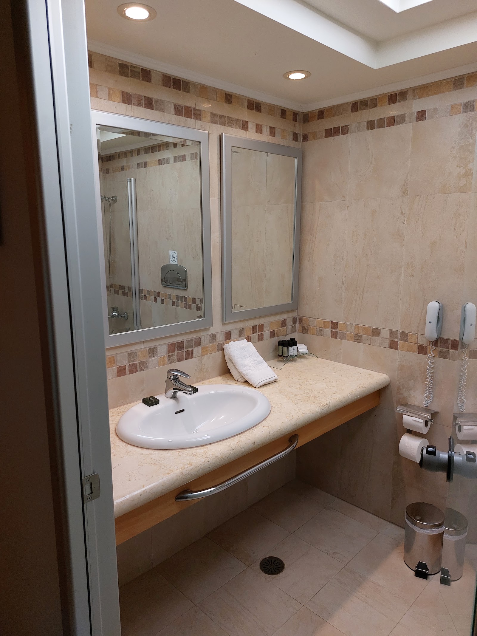 Bathroom with beige tile walls, decorative tile border, white oval sink on stone countertop, and mirrored medicine cabinet above.