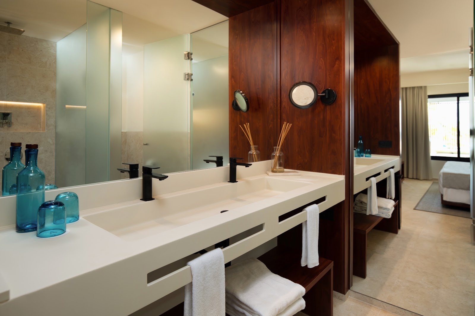 Suite with sunken jetted tub, daybed with pillows, and slatted shade screen overlooking resort grounds.
