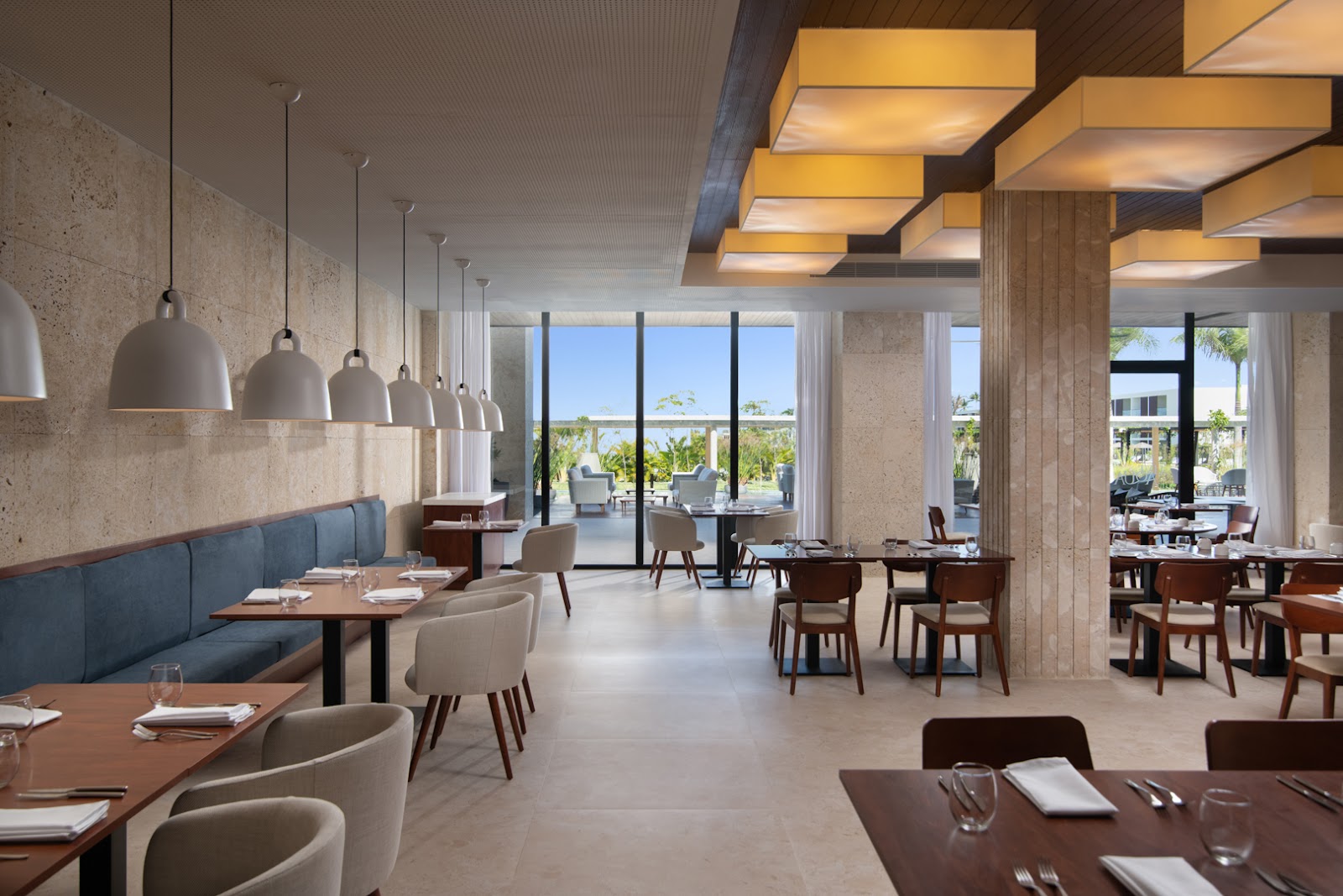 Open-air dining terrace with set tables, green chairs, wood ceiling, and views of pool and landscaped grounds at Live Aqua Beach Resort Punta Cana.