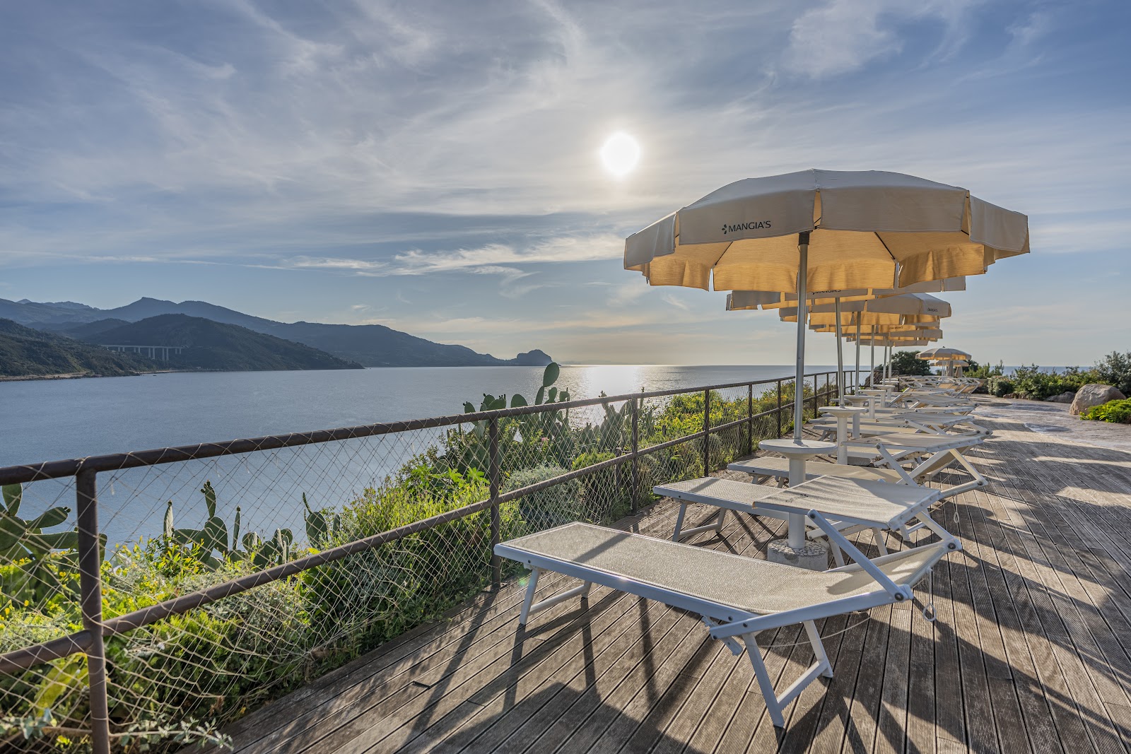 Dining table set for four with sea and cliff views through floor-to-ceiling windows at Mangia's Pollina Resort.
