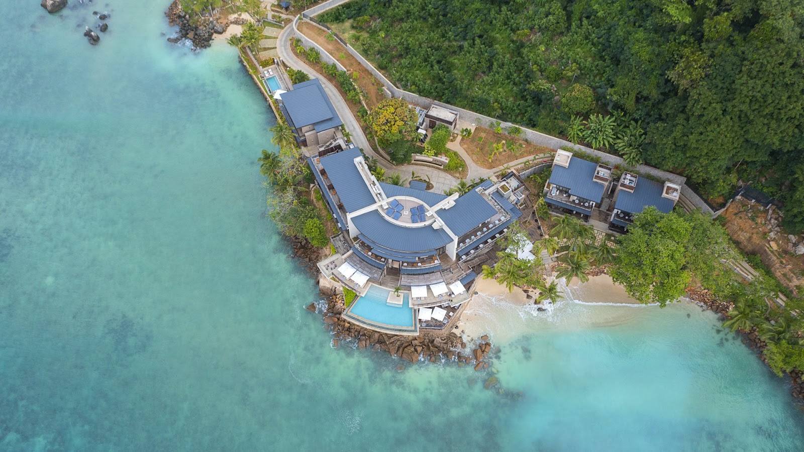 Guests prepare kayaks in the shallow turquoise water at Mango House Seychelles, with a yellow and white kayak beached in the foreground.